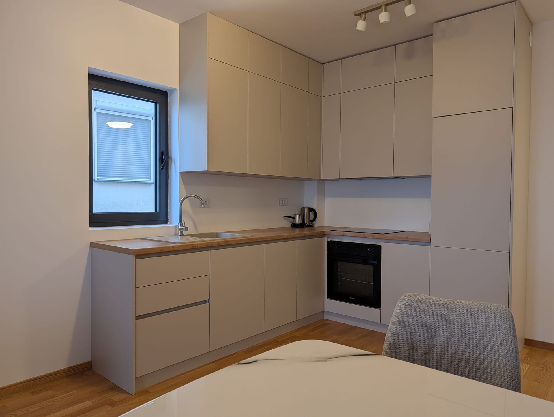 Moderna kuhinja u svetlim tonovima sa drvenom radnom pločom u apartmanima, Bečići, Crna Gora.