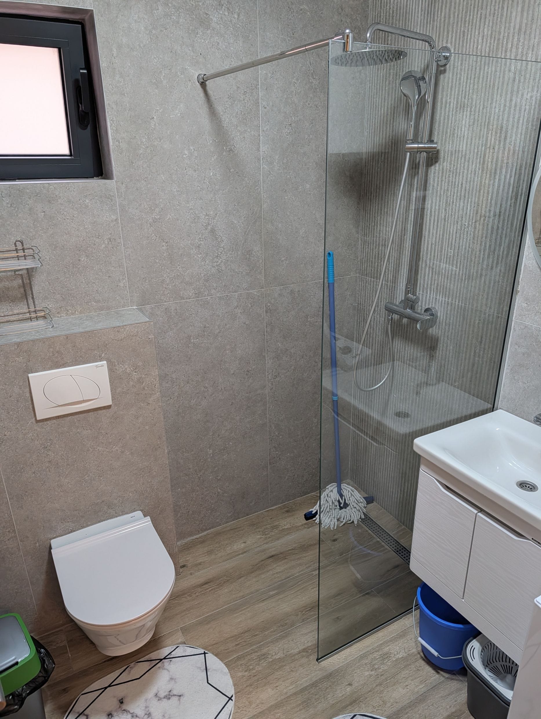 Moderno kupatilo sa tuš kabinom i sivim pločicama u apartmanima u Bečićima, Crna Gora.