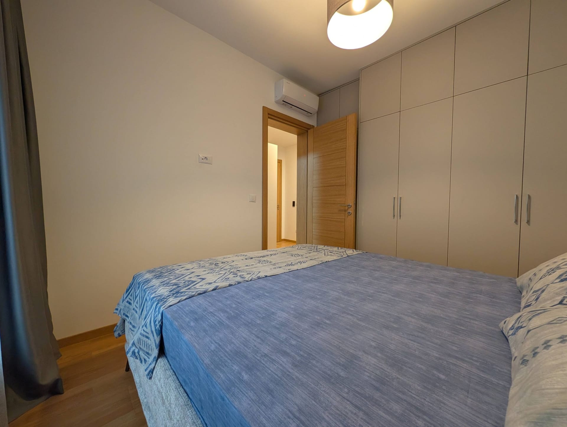 Moderna spavaća soba u apartmanima u Bečićima, Crna Gora: bračni krevet, ugradbeni ormar i klima uređaj.