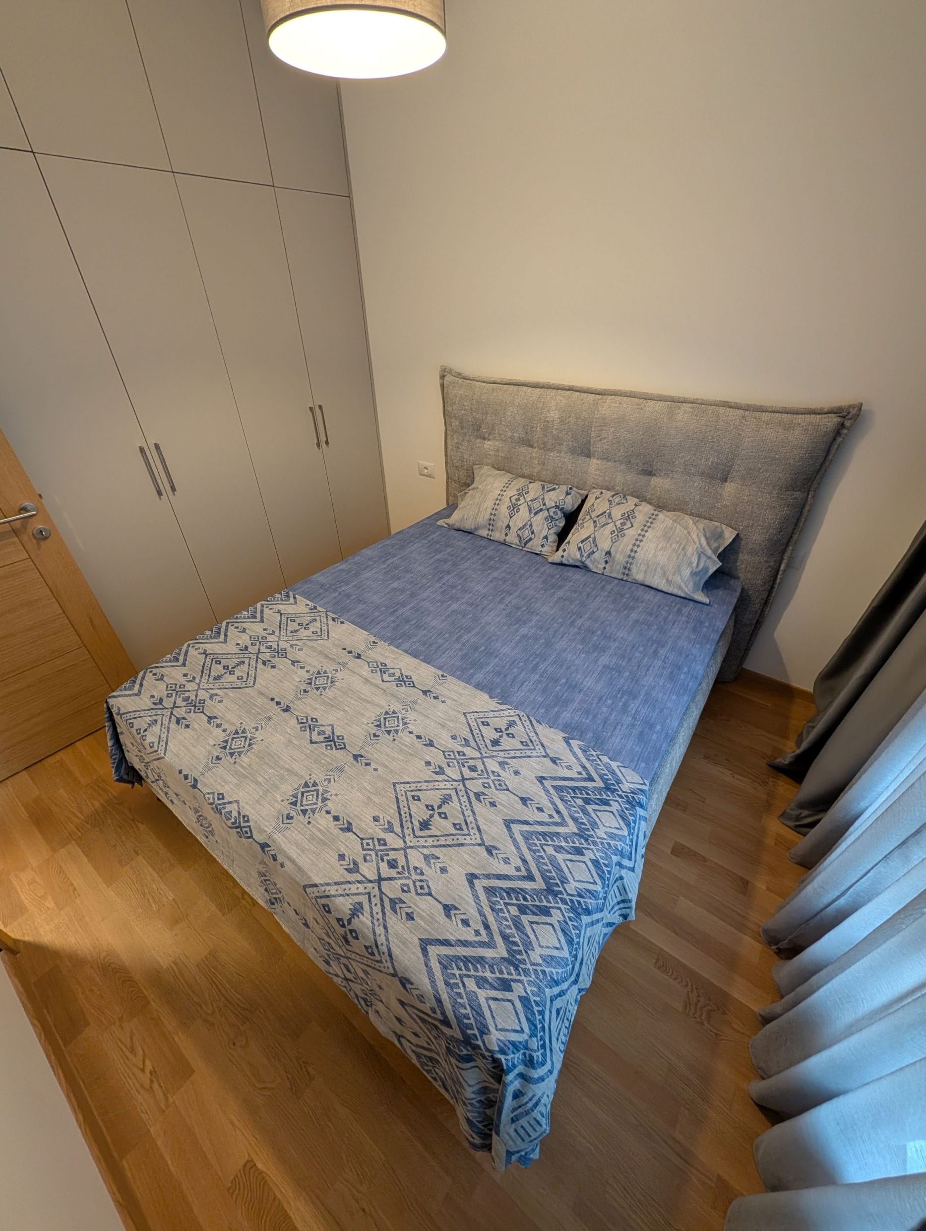 Udobna spavaća soba sa bračnim krevetom i ugradbenim ormarom u apartmanu u Bečićima, Crna Gora. Moderan enterijer.