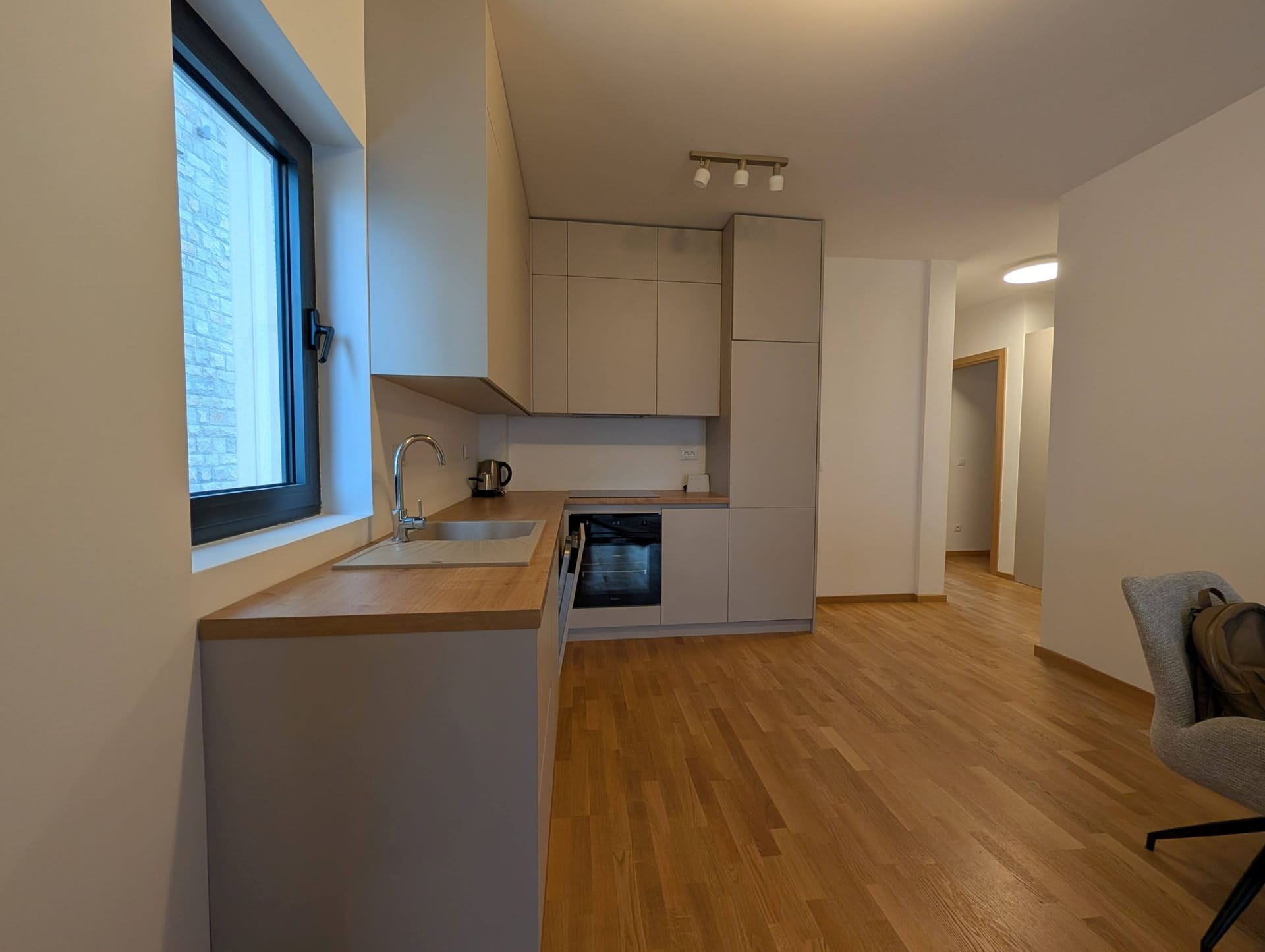 Moderna kuhinja sa svetlim fasadama i drvenom radnom pločom u apartmanima u Bečićima, Crna Gora.