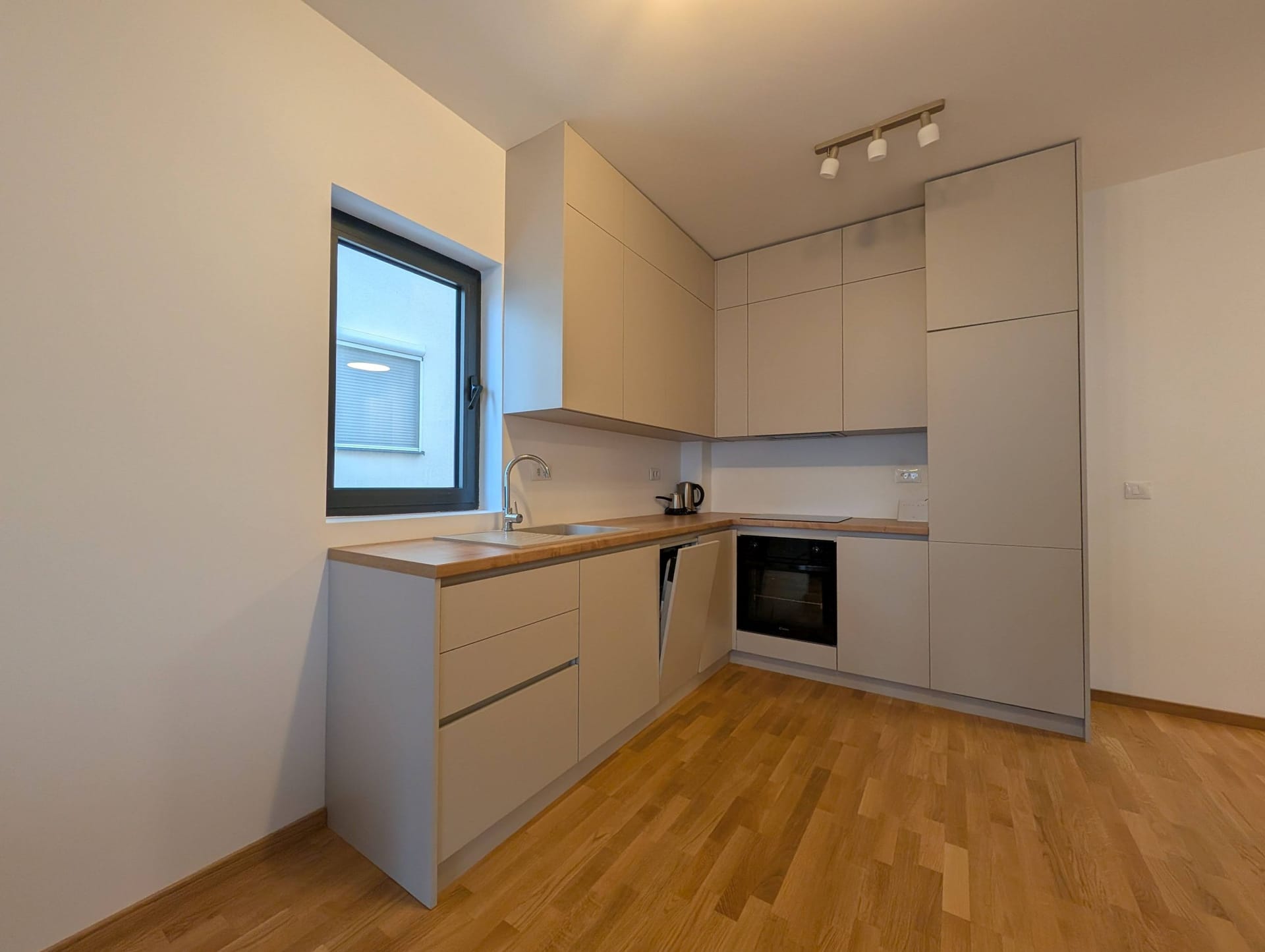 Moderna kuhinja u svetlim tonovima sa drvenom radnom pločom u apartmanima, Bečići, Crna Gora.