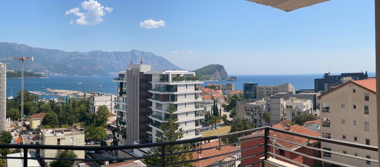 Panoramski pogled sa balkona stana u Budvi, Crna Gora: more, ostrvo Svetog Nikole i gradska izgradnja.