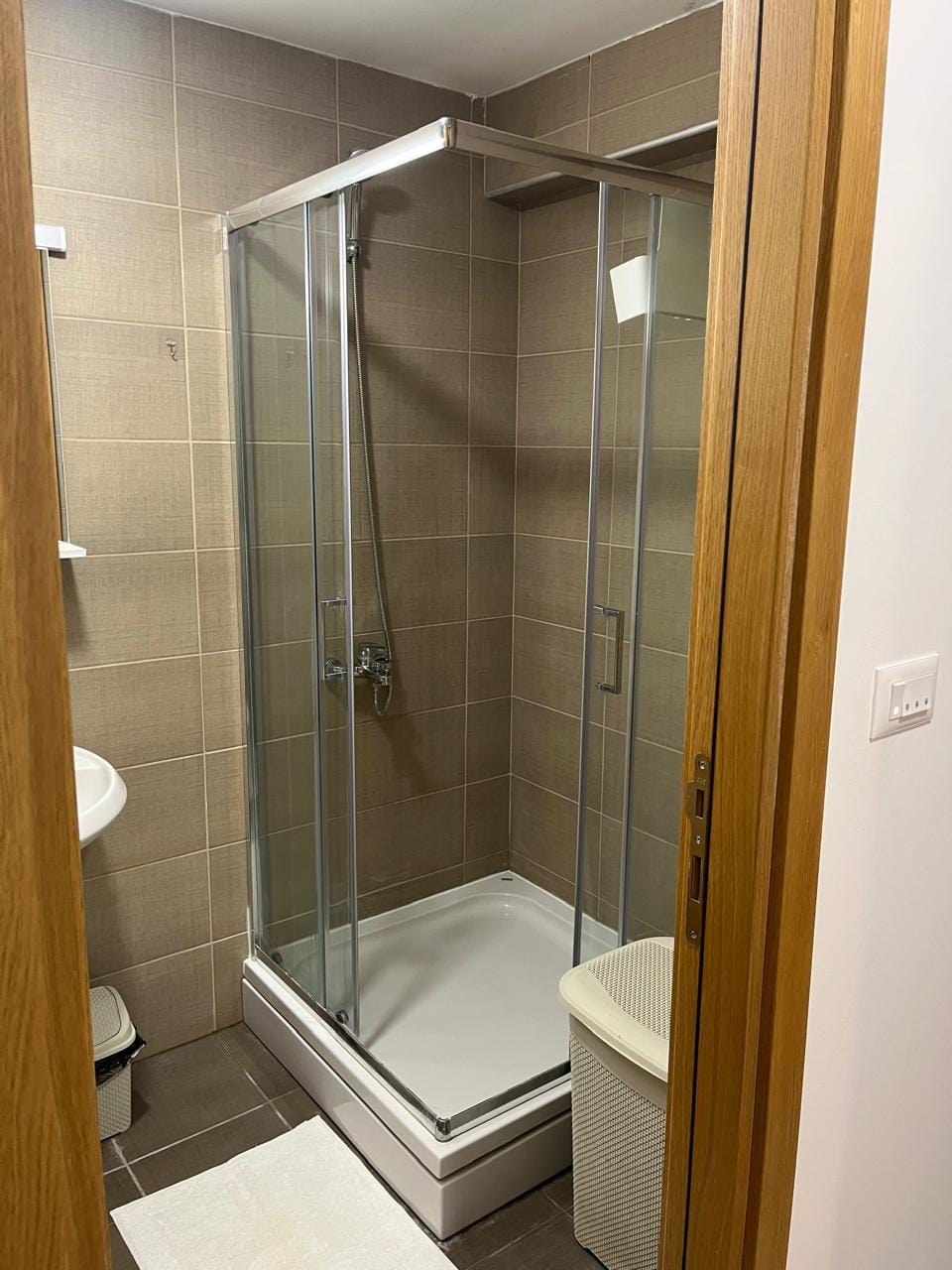 Kupatilo sa tuš kabinom u stanu u Budvi, Crna Gora: moderna obrada pločicama i sanitarije.