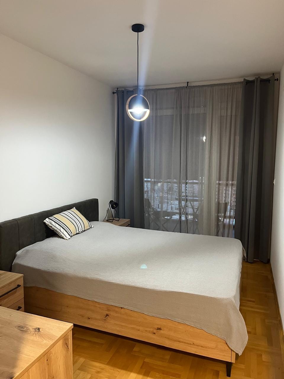 Moderna spavaća soba sa bračnim krevetom i izlazom na balkon u stanu, Budva, Crna Gora.