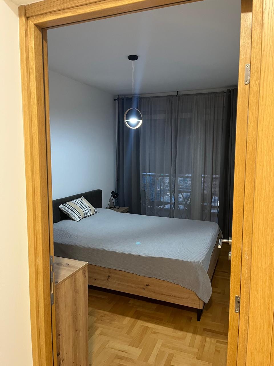 Udobna spavaća soba sa bračnim krevetom i parketom u modernom stanu, Budva, Crna Gora.