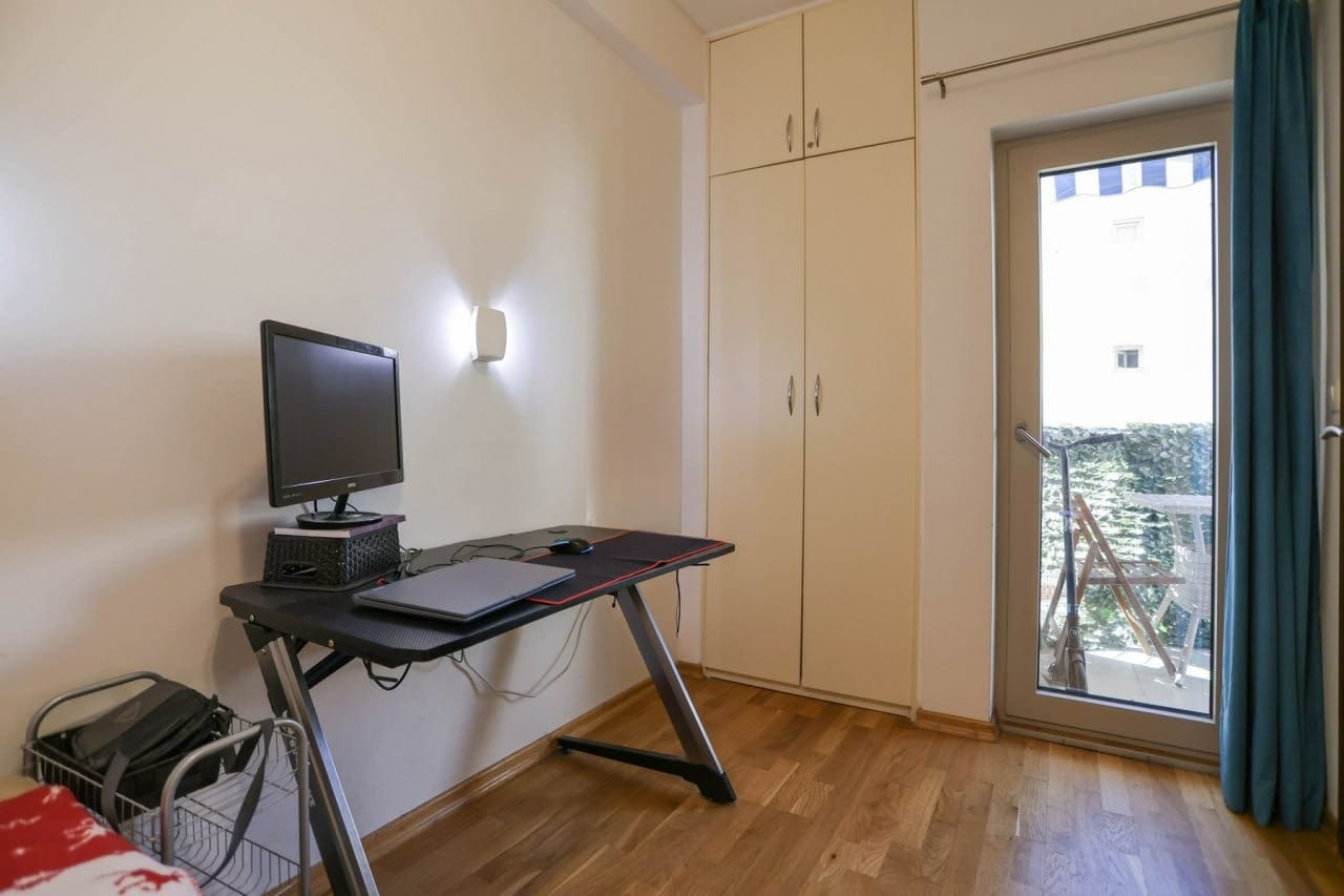 Spavaća soba u stanu u Budvi, Crna Gora: radni sto, ugradni ormar, parket i izlaz na balkon.