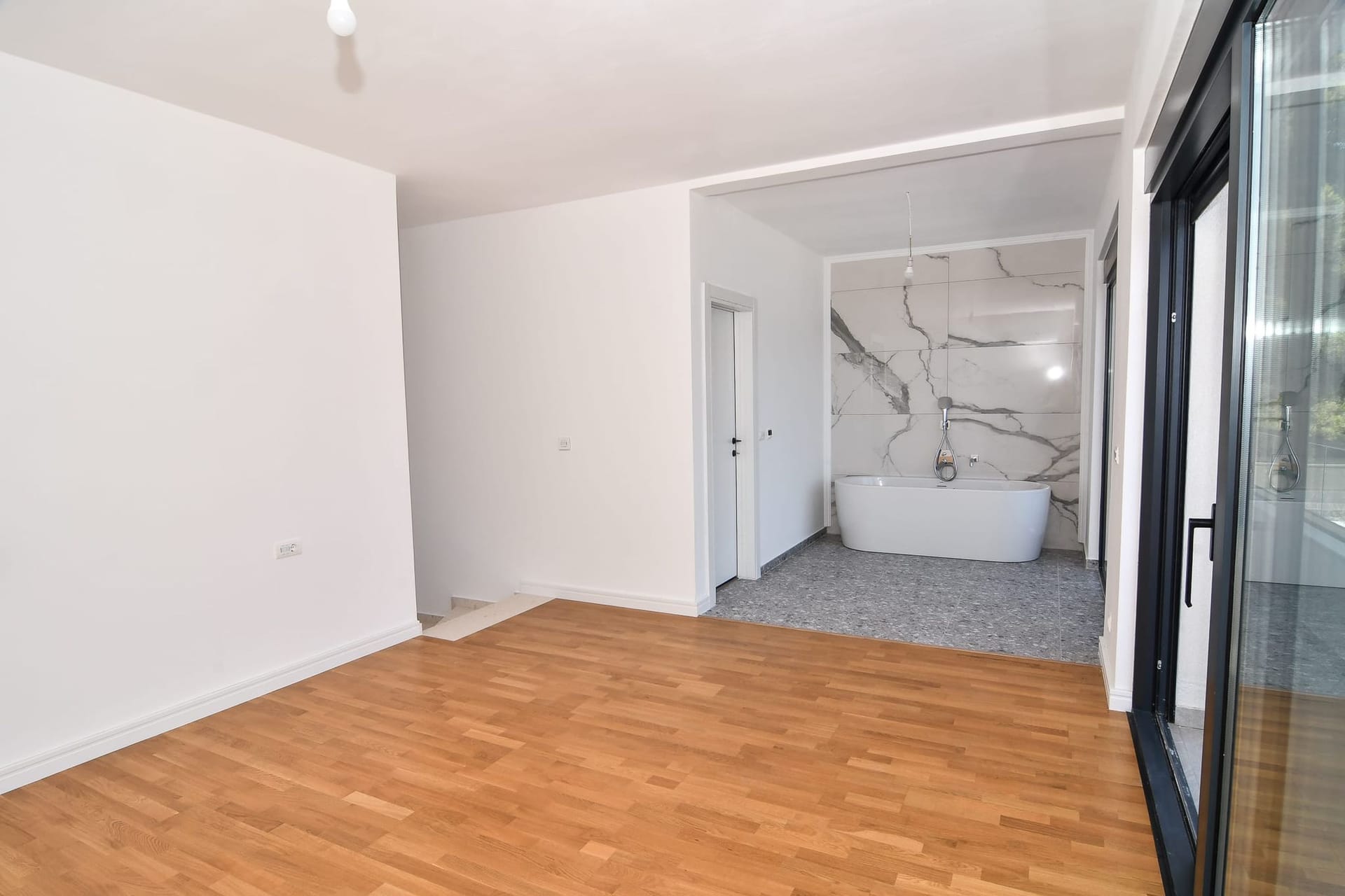 Spavaća soba sa kupatilom u modernoj vili u Budvi, Crna Gora: parket, panoramski prozori i mermerna završna obrada.