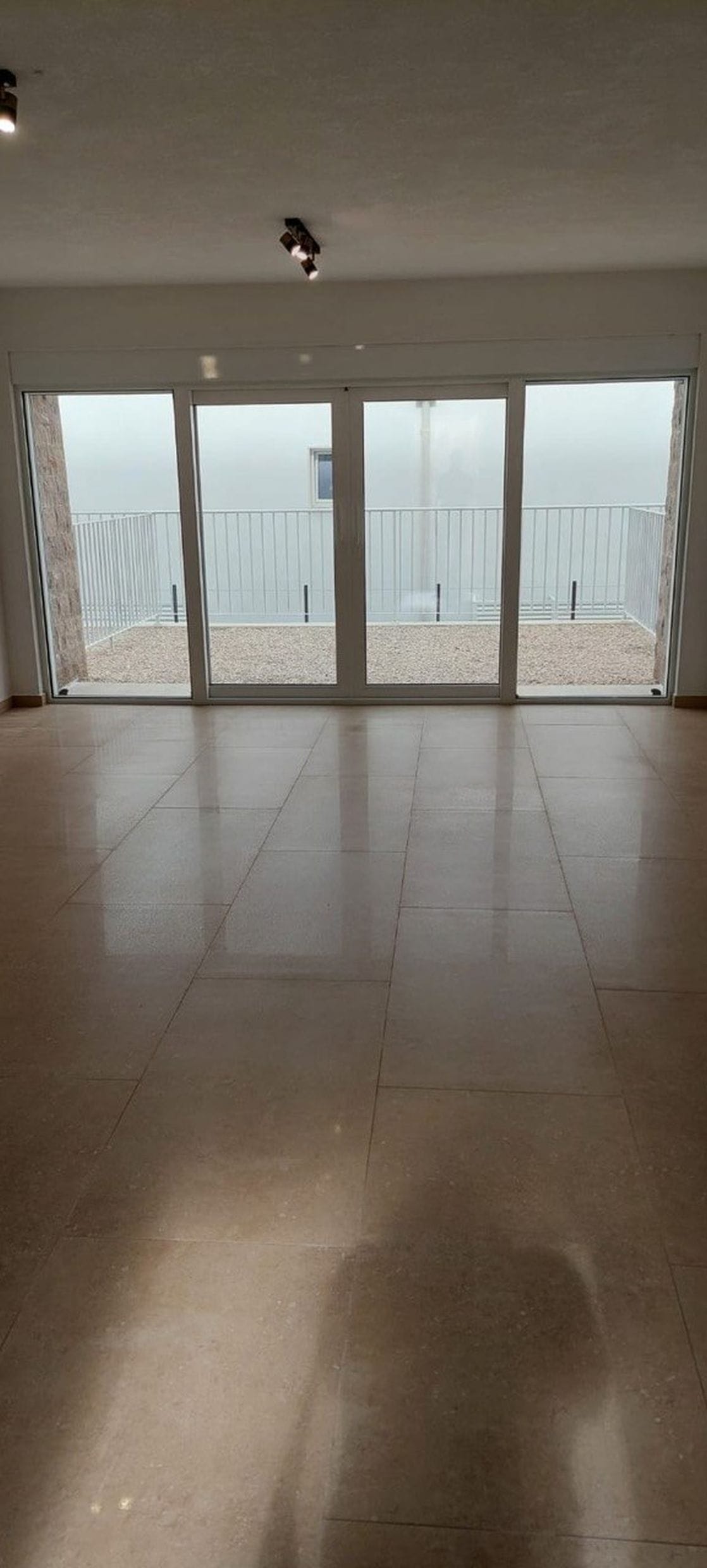 Svetla dnevna soba u townhouseu, Luštica, Crna Gora: panoramski prozori, izlaz na terasu i mermerni pod.
