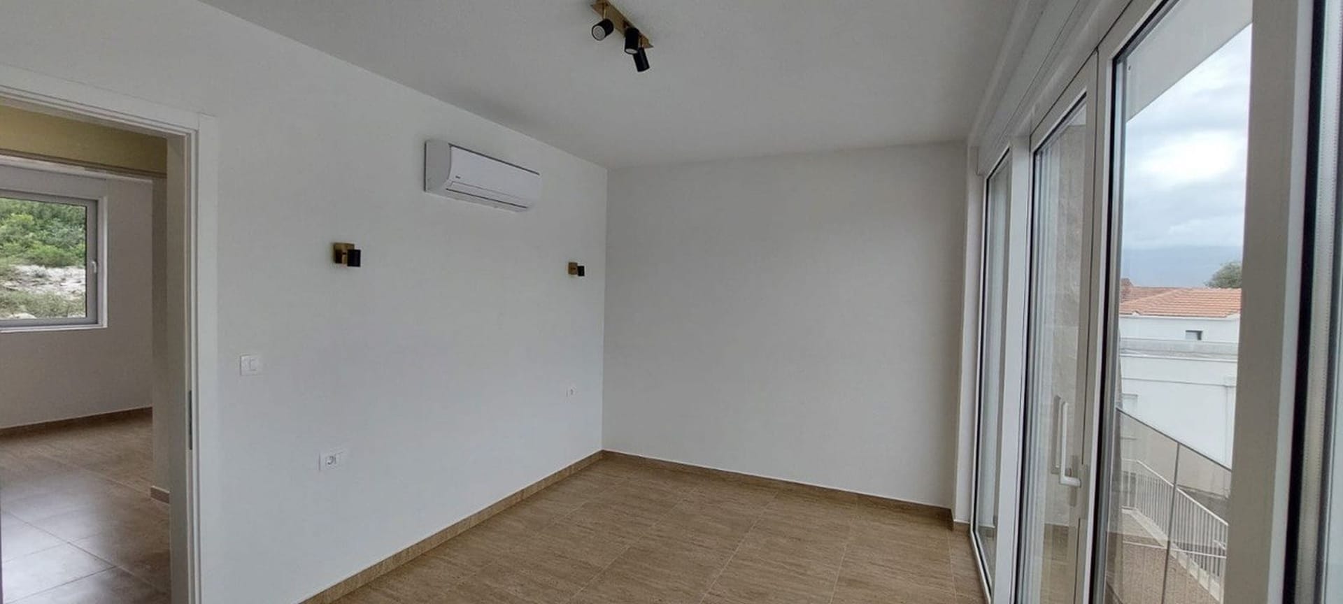 Svetla dnevna soba u taunhausu, Luštica, Crna Gora: panoramski prozori, pločice na podu, klima-uređaj i moderan dekor.