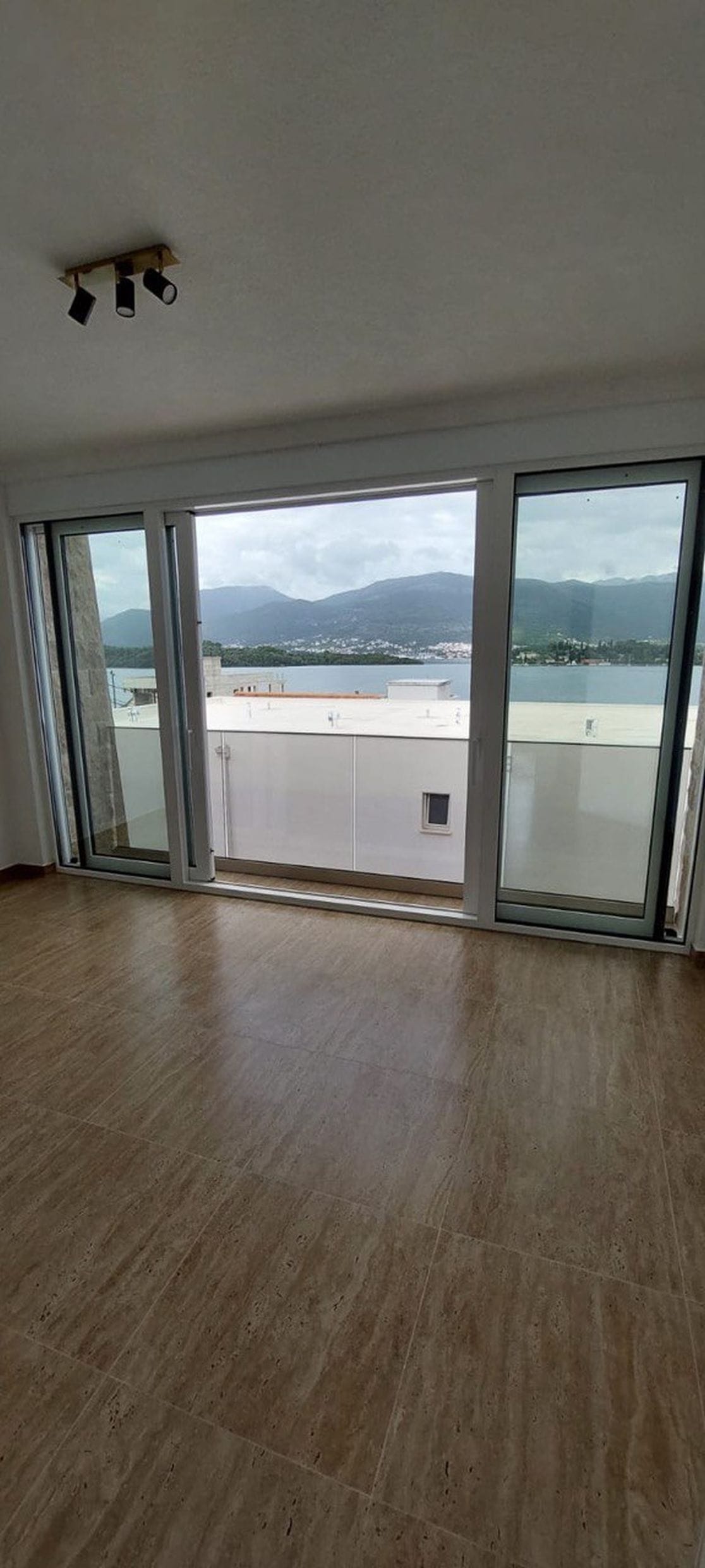 Dnevna soba s panoramskim prozorima i pogledom na more i planine u townhouseu, Luštica, Crna Gora: svetao enterijer, pločice.