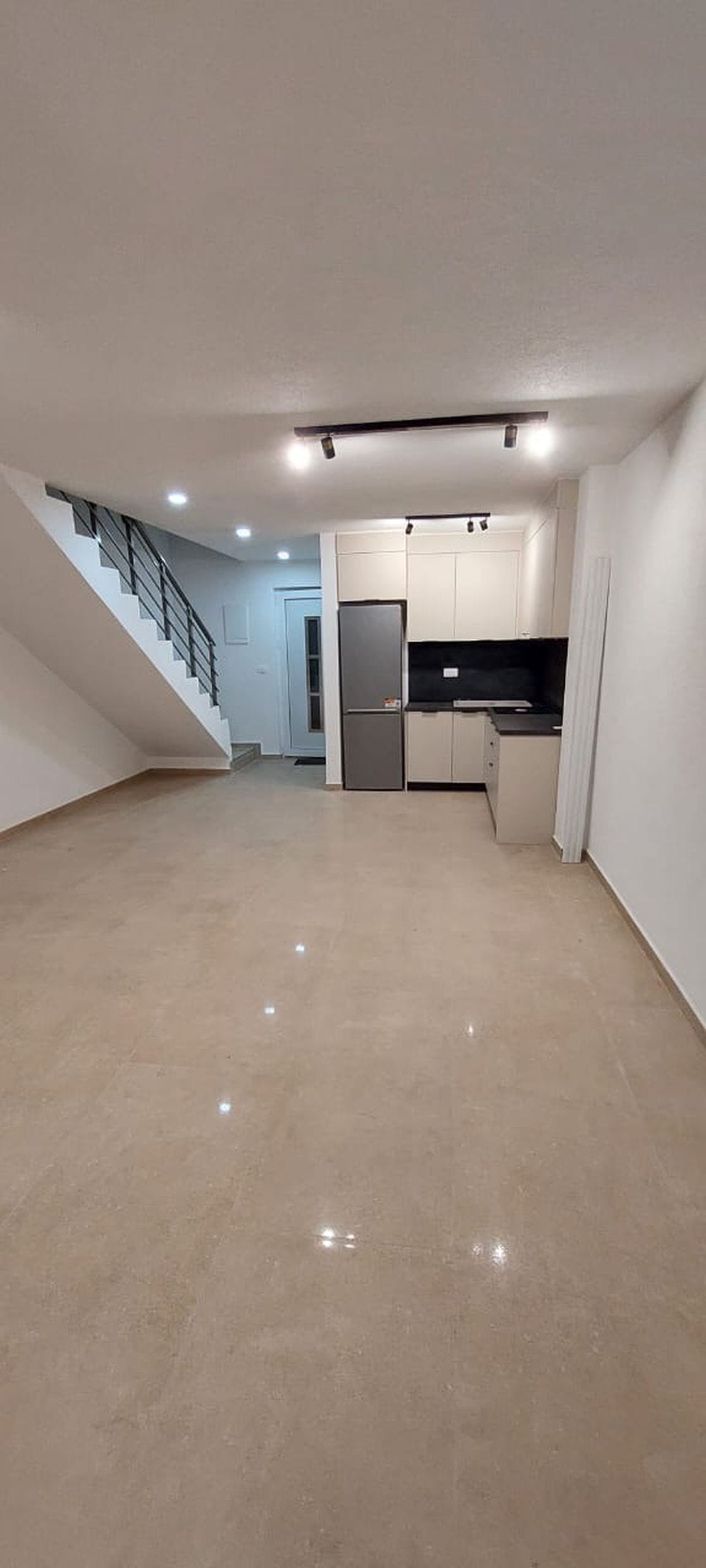 Dnevna soba sa kuhinjom i stepeništem u townhouseu, Luštica, Crna Gora: moderan enterijer, svetle pločice, ugradni nameštaj.