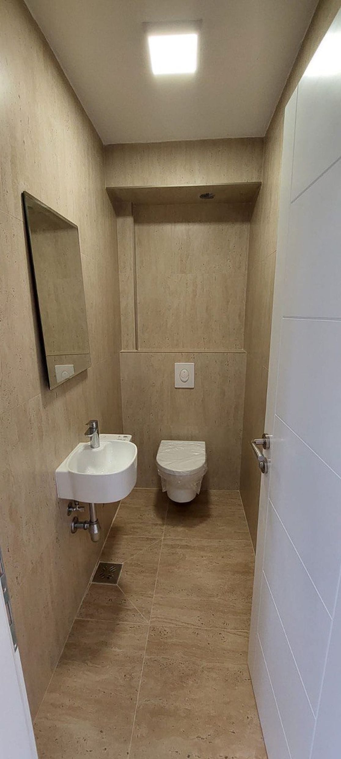 Moderan sanitarni čvor sa belom sanitarnom opremom i bež pločicama u taunhausu, Luštica, Crna Gora.