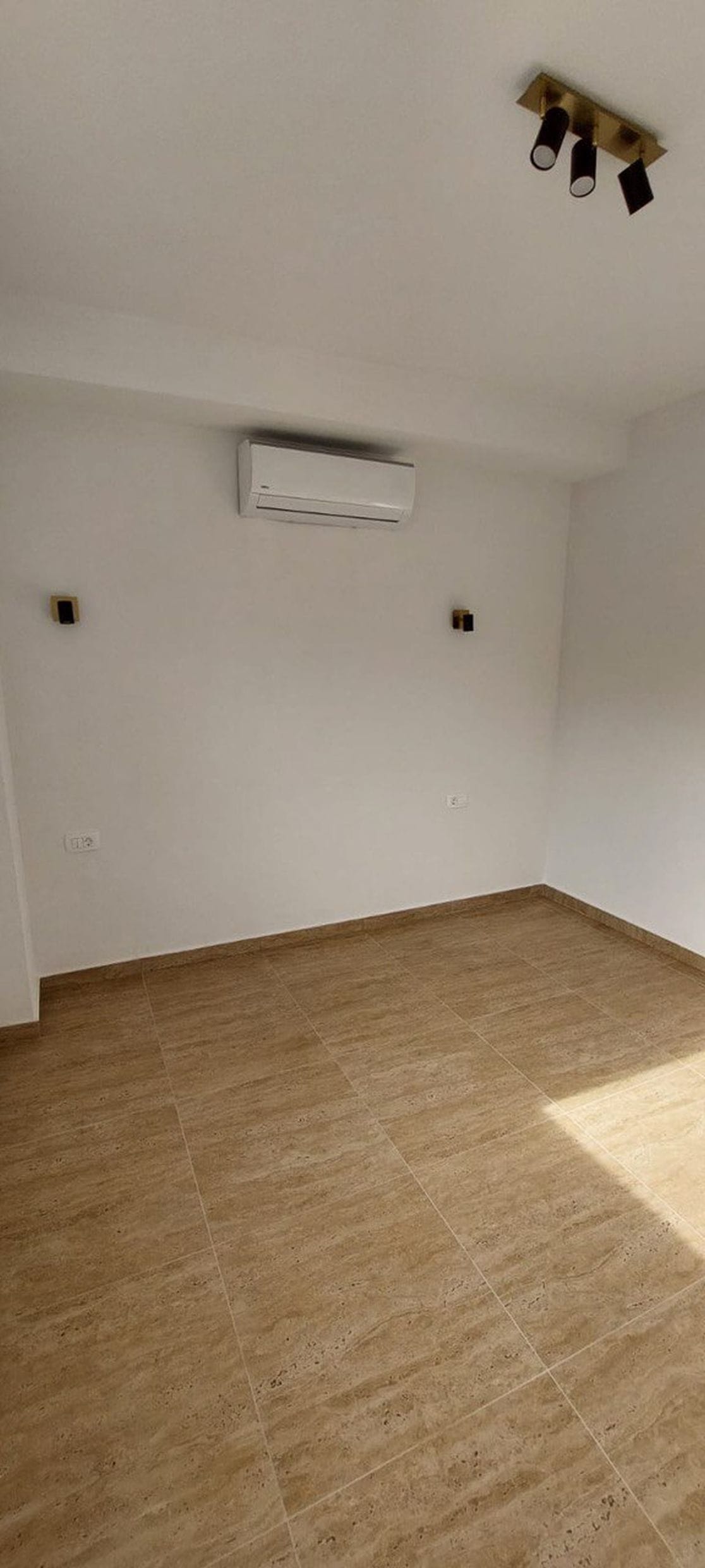 Svetla spavaća soba u townhouseu, Luštica, Crna Gora: beli zidovi, pločice na podu, klima-uređaj i moderno osvetljenje.