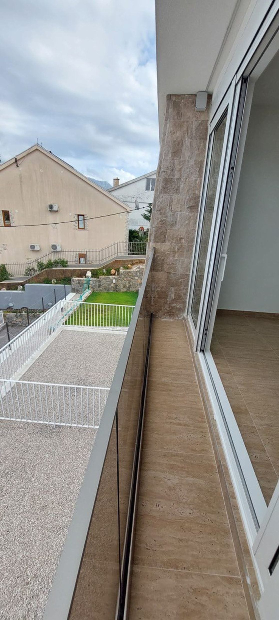 Balkon sa panoramskim zastakljenjem i kamenim oblogama u taunhausu, Luštica, Crna Gora. Pogled na unutrašnje dvorište kuće.