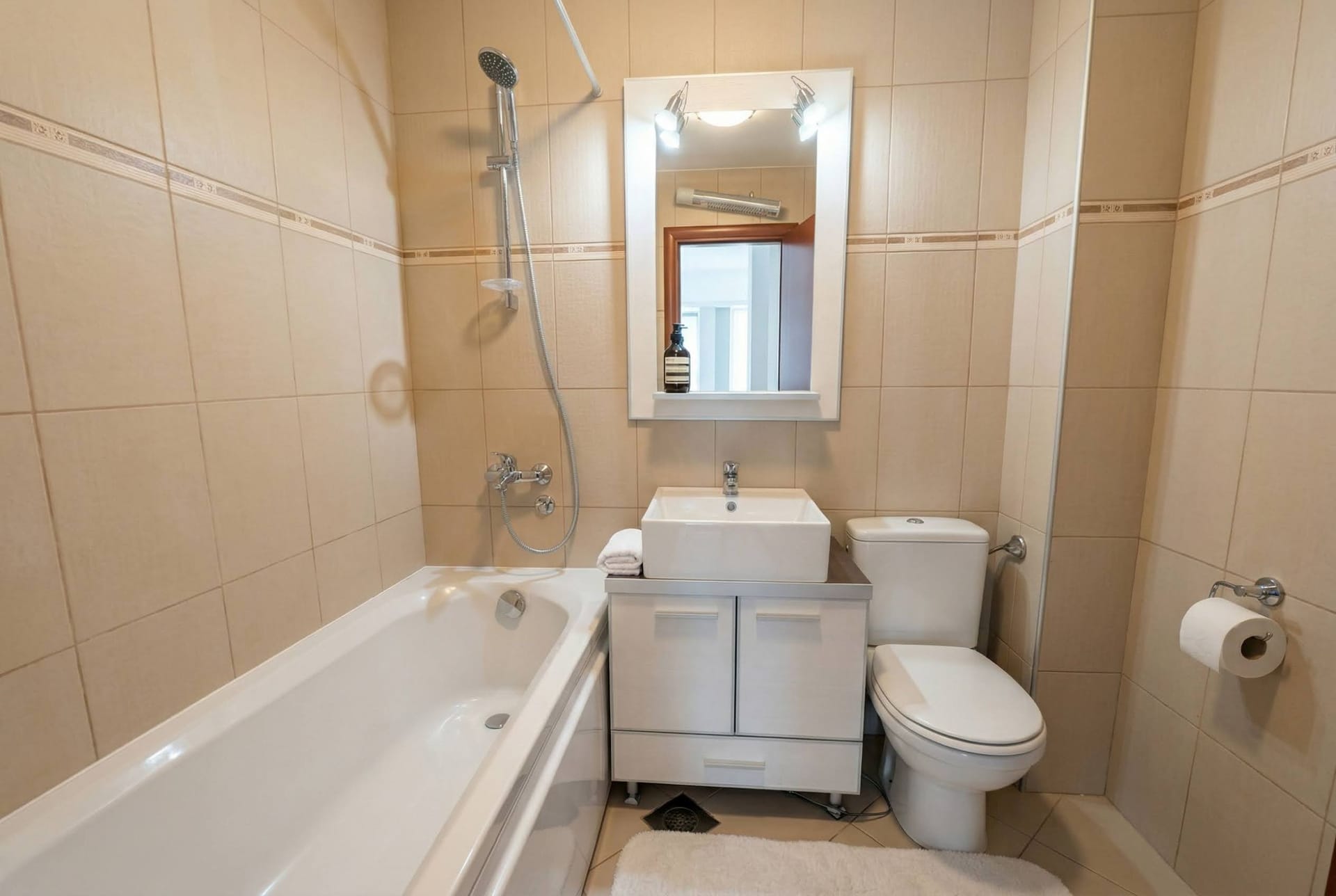 Kupatilo sa belom sanitarnom opremom i bež pločicama u stanu u Bečićima, Crna Gora. Moderan enterijer.