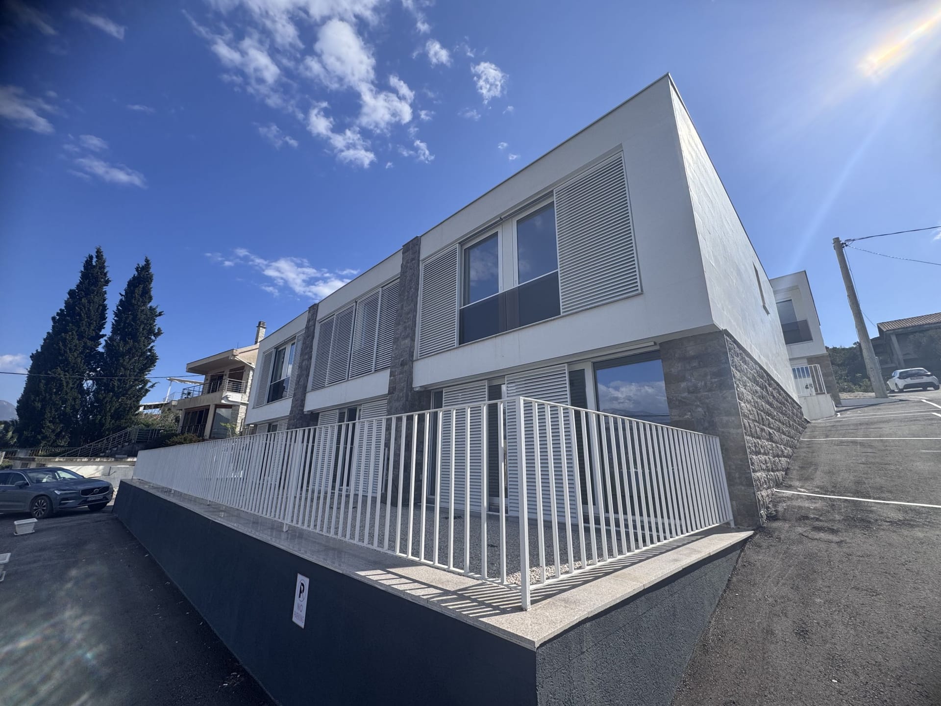 Moderan dvospratni townhouse sa belom fasadom i kamenim oblogama u Luštici, Crna Gora, pogled spolja.
