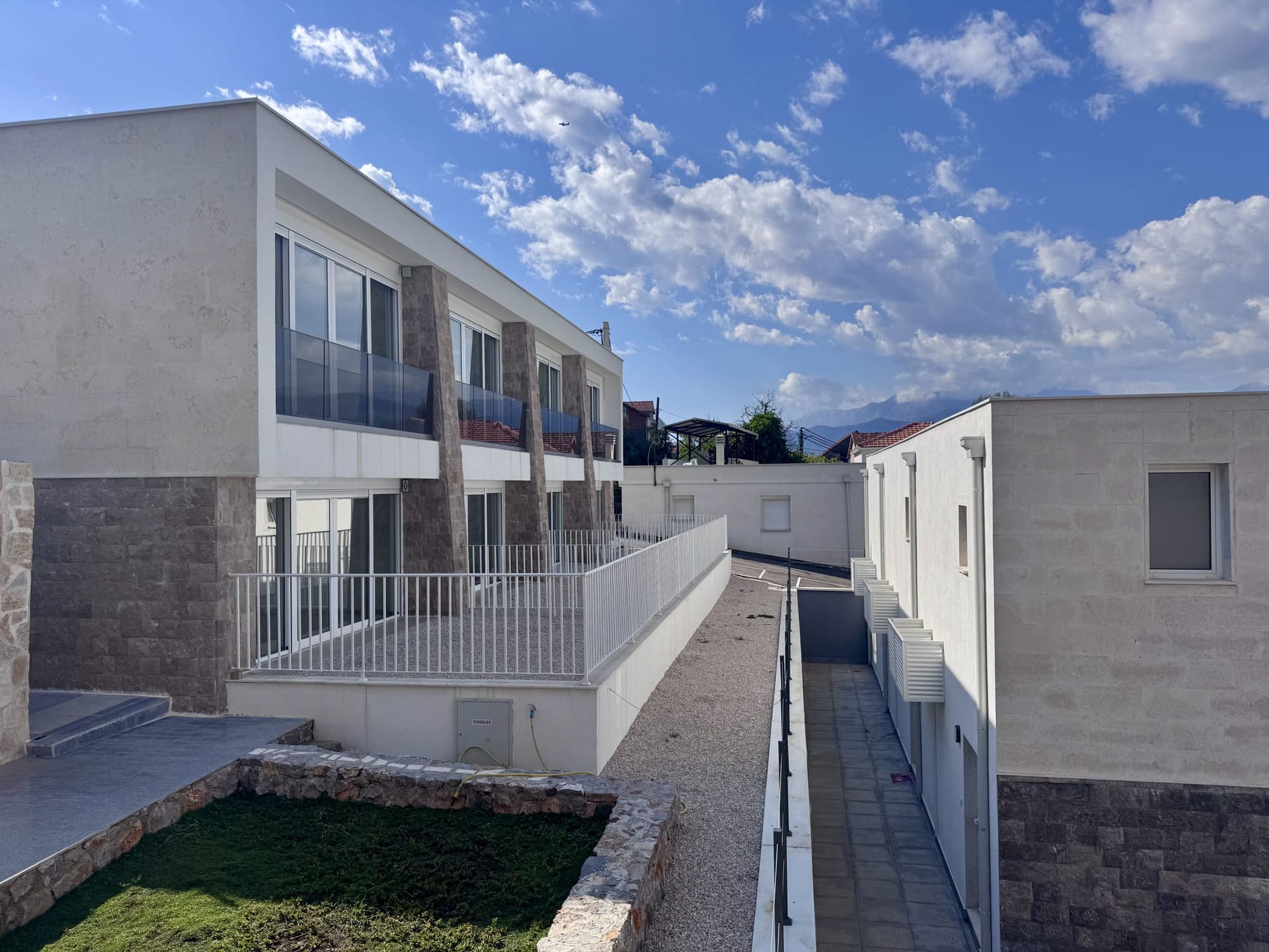 Moderan townhouse sa terasama i kamenim oblogama fasade u Luštici, Crna Gora, pogled na stambeni kompleks spolja.