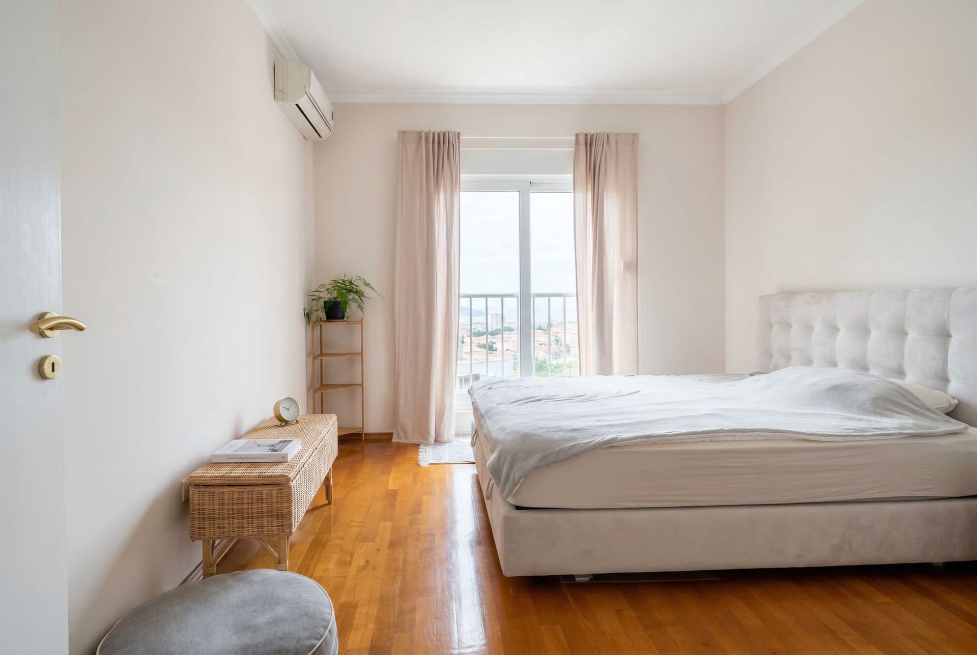 Svetla spavaća soba sa bračnim krevetom, parketom i izlazom na balkon u stanu u Budvi, Crna Gora.