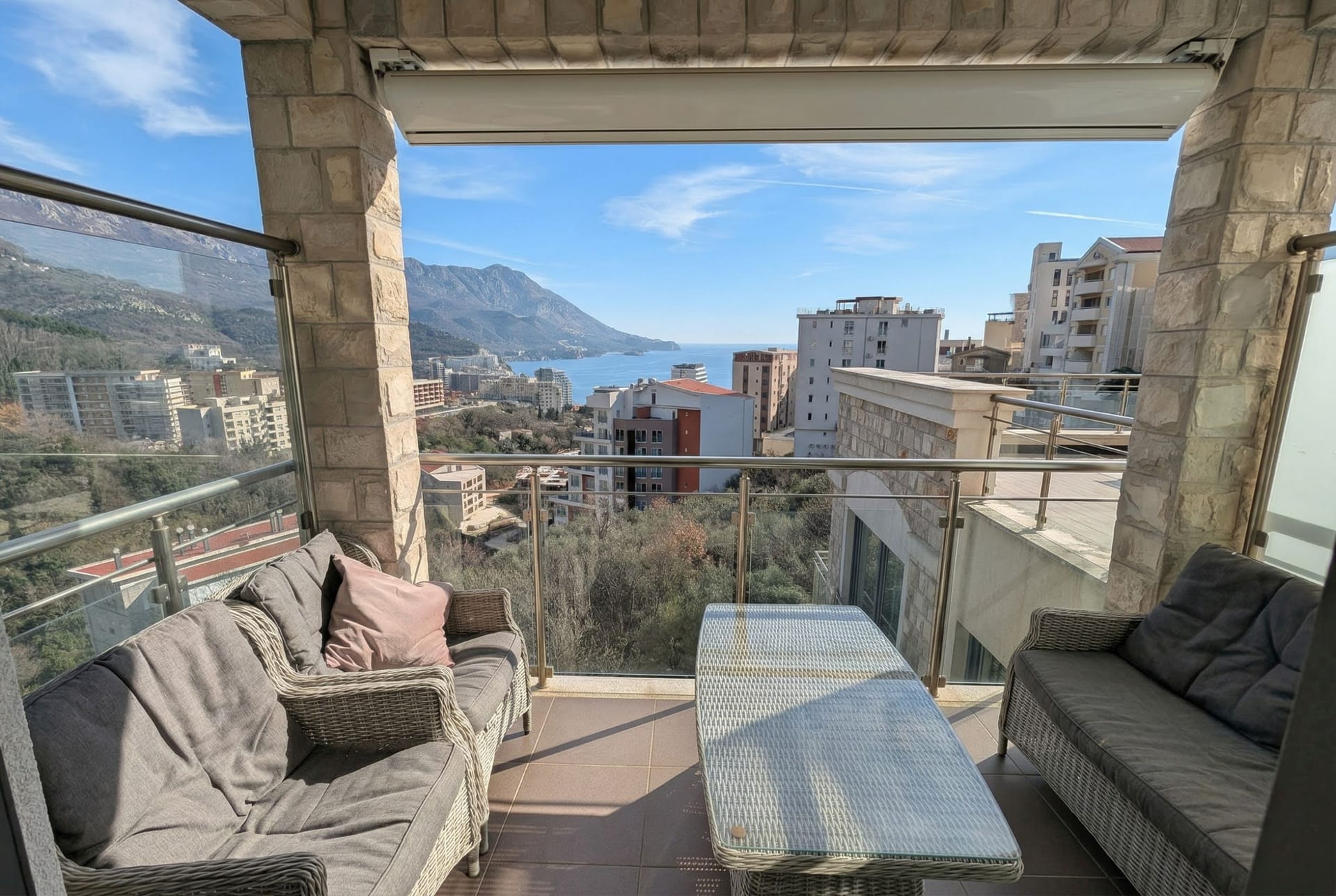 Terasa sa pletenim nameštajem i panoramskim pogledom na more i planine u stanu, Bečići, Crna Gora.