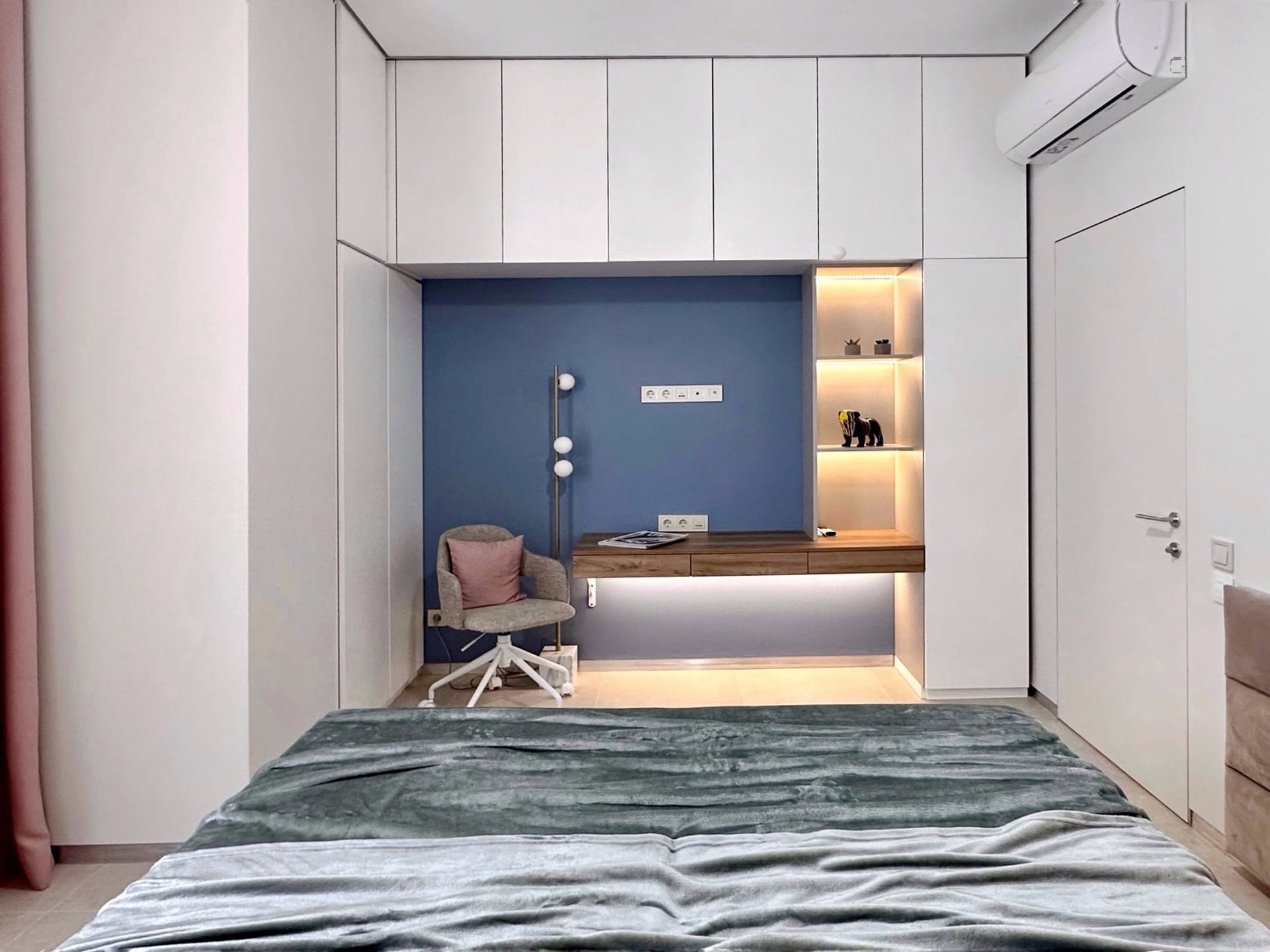 Chambre moderne dans un appartement à Bečići, Monténégro : placard intégré, espace de travail avec éclairage et fauteuil moelleux.