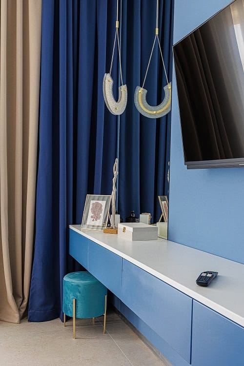 Intérieur moderne du salon dans un appartement à Bečići, Monténégro : mobilier bleu, luminaires design et espace TV.