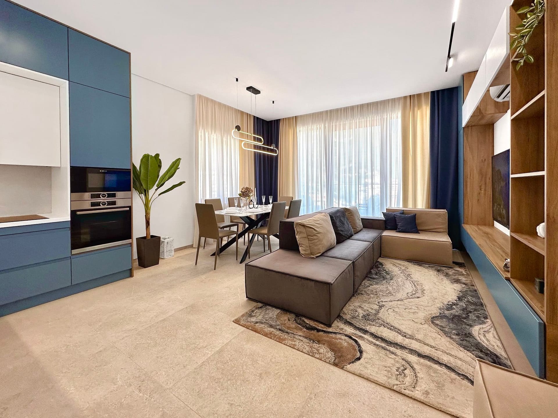 Salon moderne avec cuisine dans un appartement à Bečići, Monténégro : mobilier élégant, baies vitrées panoramiques et intérieur chaleureux.
