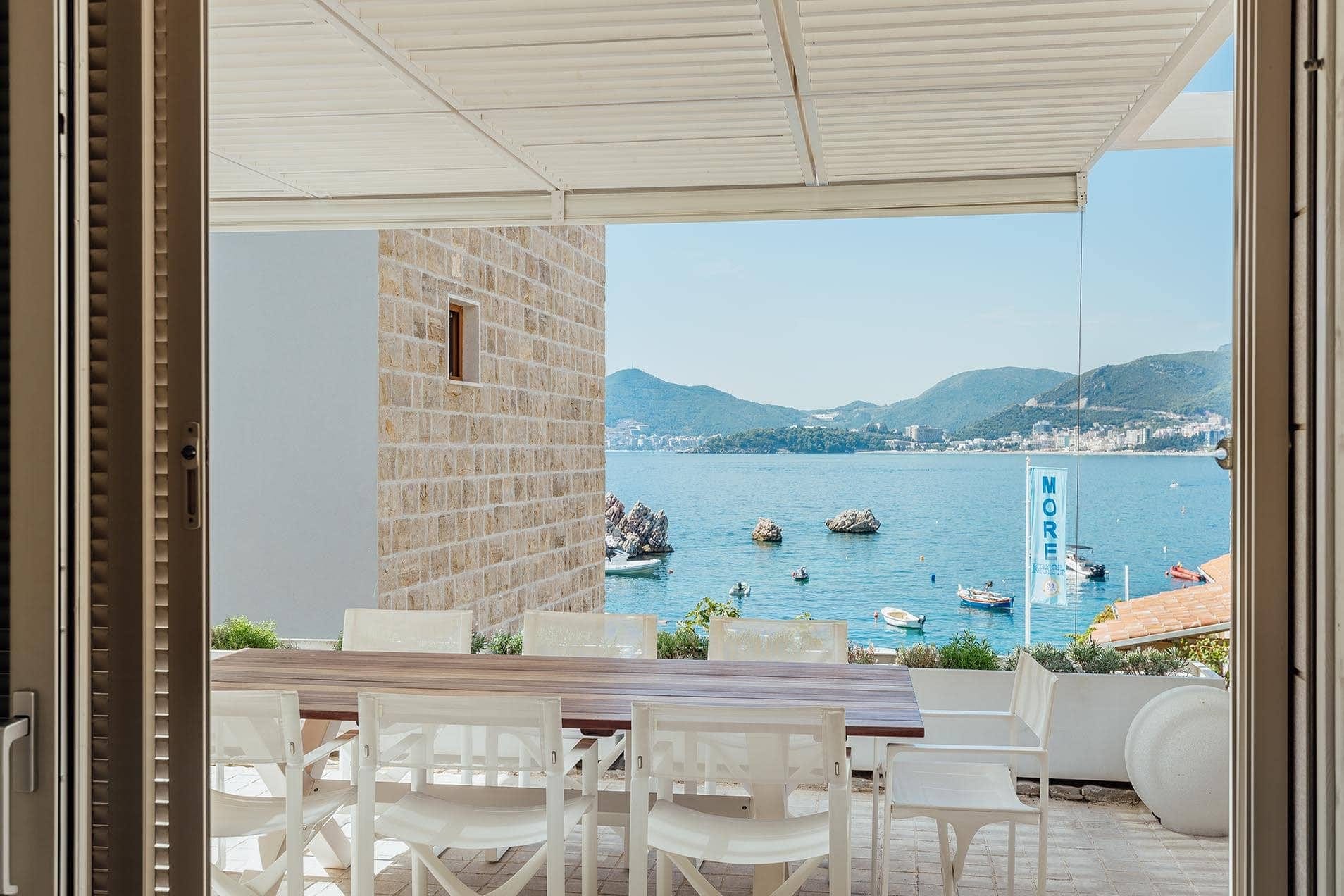Villa terrace in Pržno, Montenegro: dining table, sea and mountain views, stone wall finish, sunshade.