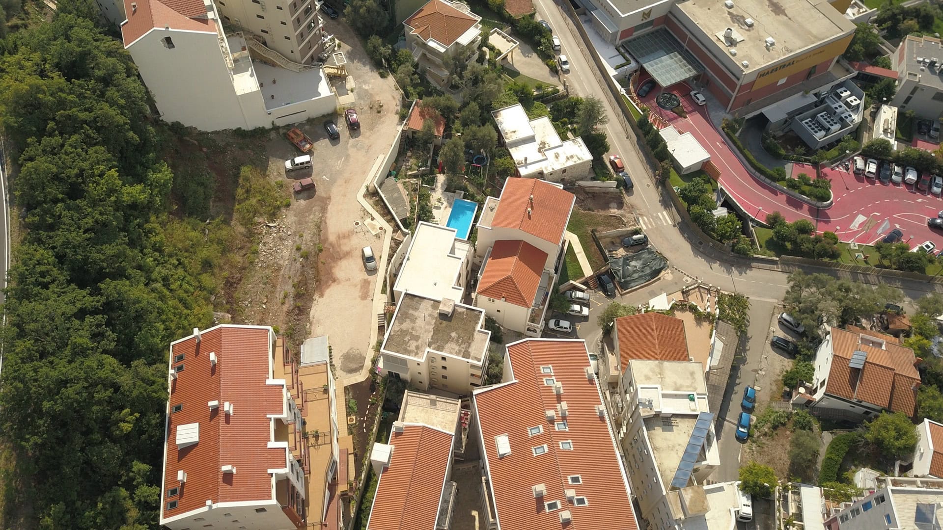Aerial view of a residential complex in Pržno, Montenegro: tiled roofs, a pool, and neighborhood infrastructure.
