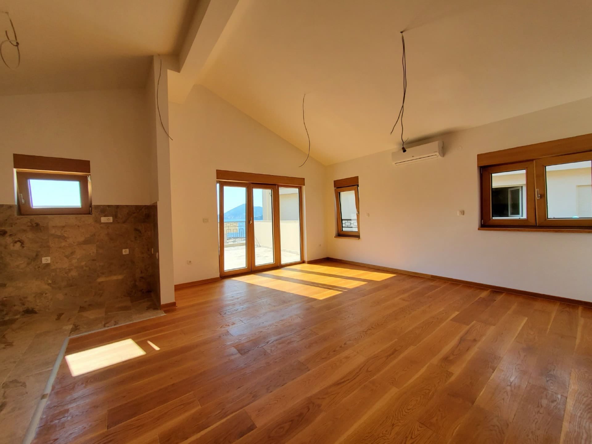 Bright living room in a penthouse, Pržno, Montenegro: parquet floor, panoramic windows with sea view and access to the terrace.