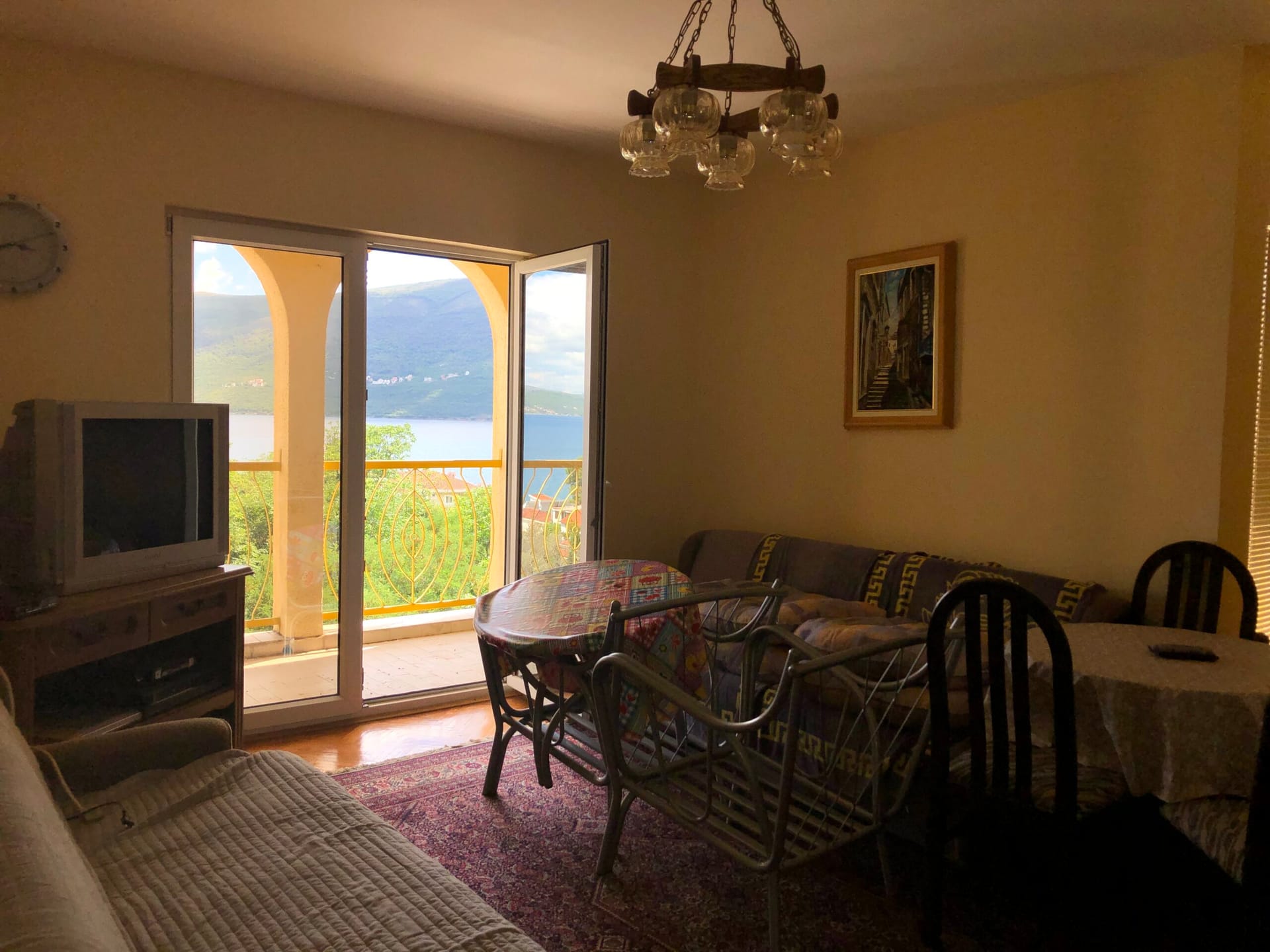 Living room in an apartment in Baošići, Montenegro: sea view from the balcony, soft seating, dining area, and classic decor.
