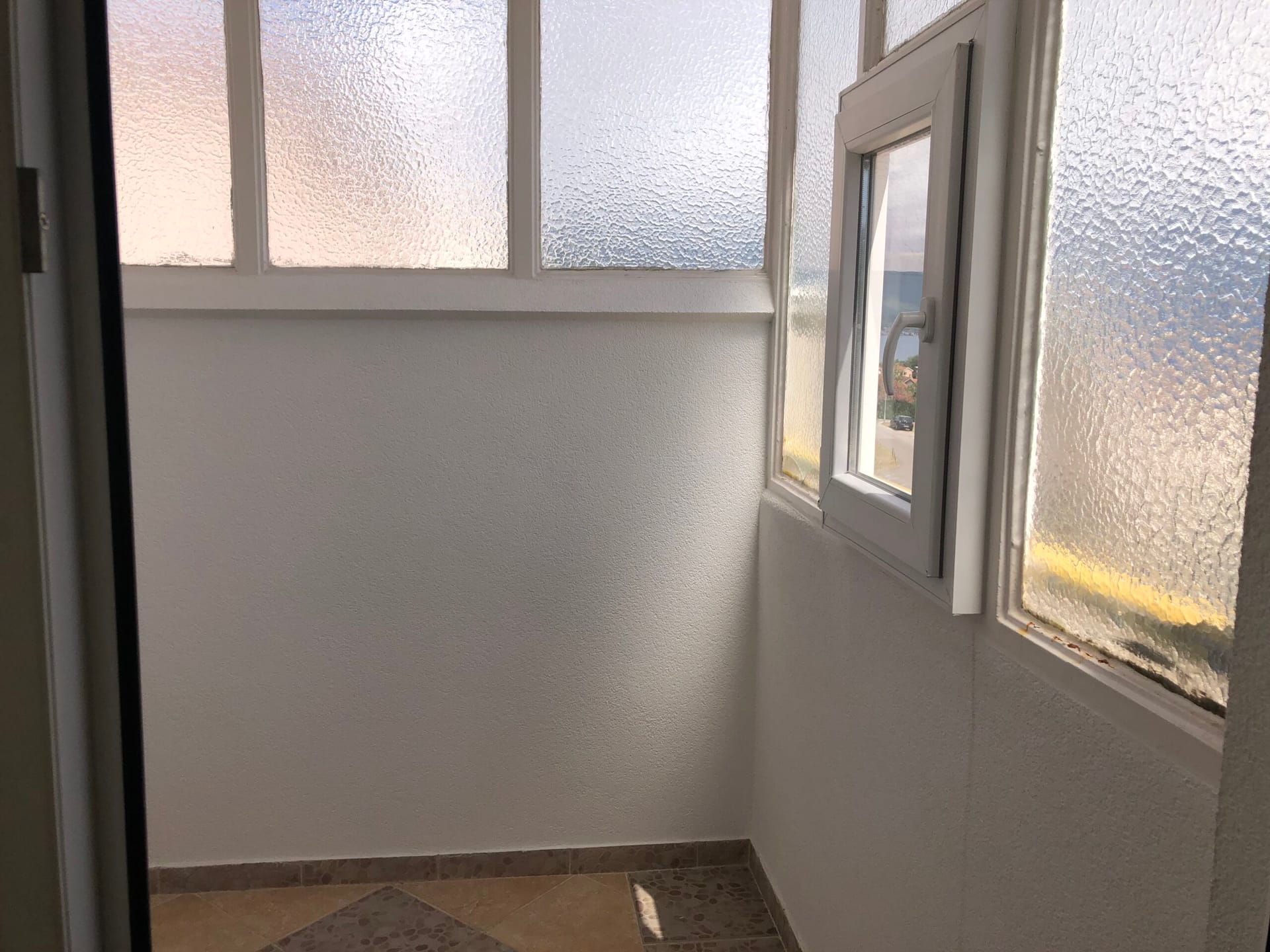 Bright balcony with panoramic glazing in an apartment, Baošići, Montenegro: sea view and tiled floor.