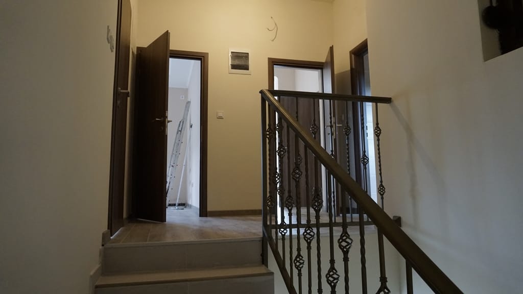 Intérieur d’une villa à Igalo, Monténégro : escalier avec rampe en fer forgé et pièces lumineuses avec portes intérieures.