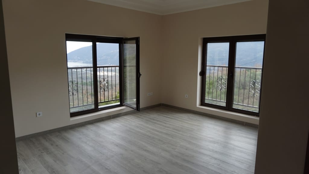 Salon lumineux avec parquet stratifié et vue panoramique sur les montagnes et la mer dans une villa, Igalo, Monténégro.