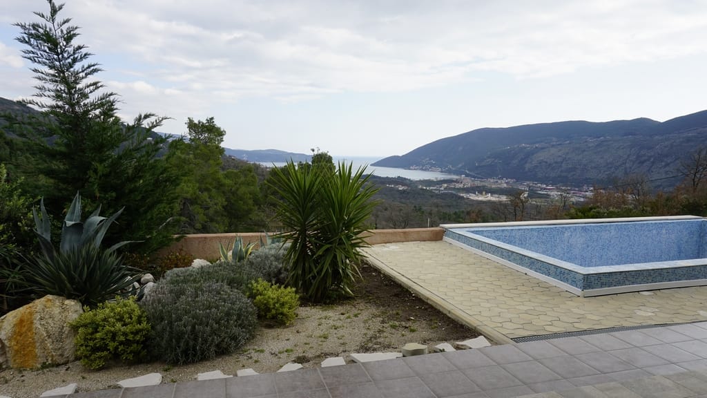 Piscine extérieure dans une villa à Igalo, Monténégro, avec vue panoramique sur les montagnes et la baie de Kotor, aménagement paysager.