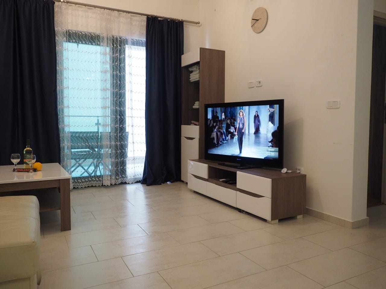 Dnevna soba u stanu u Pržnu, Crna Gora: moderan nameštaj, TV zona, panoramski prozor sa izlazom na balkon.