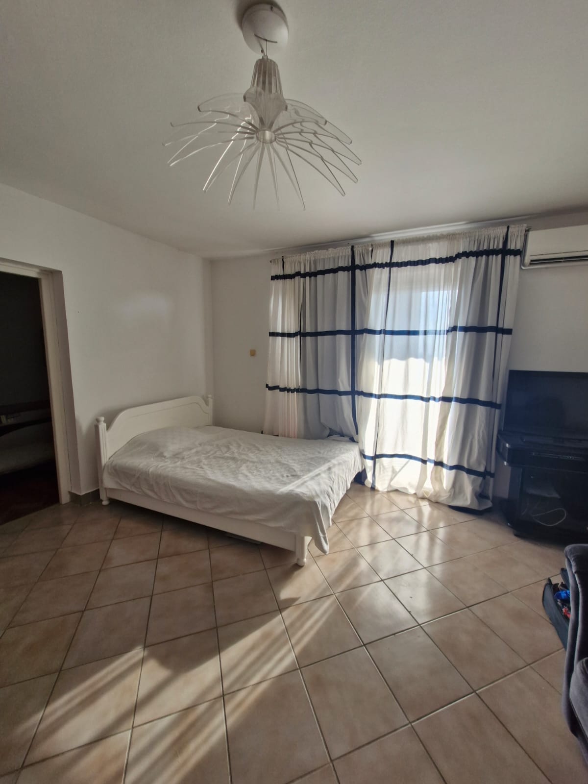 Bright bedroom with a double bed in an apartment, Sveti Stefan, Montenegro: tiled floor, air conditioning, and panoramic curtains.