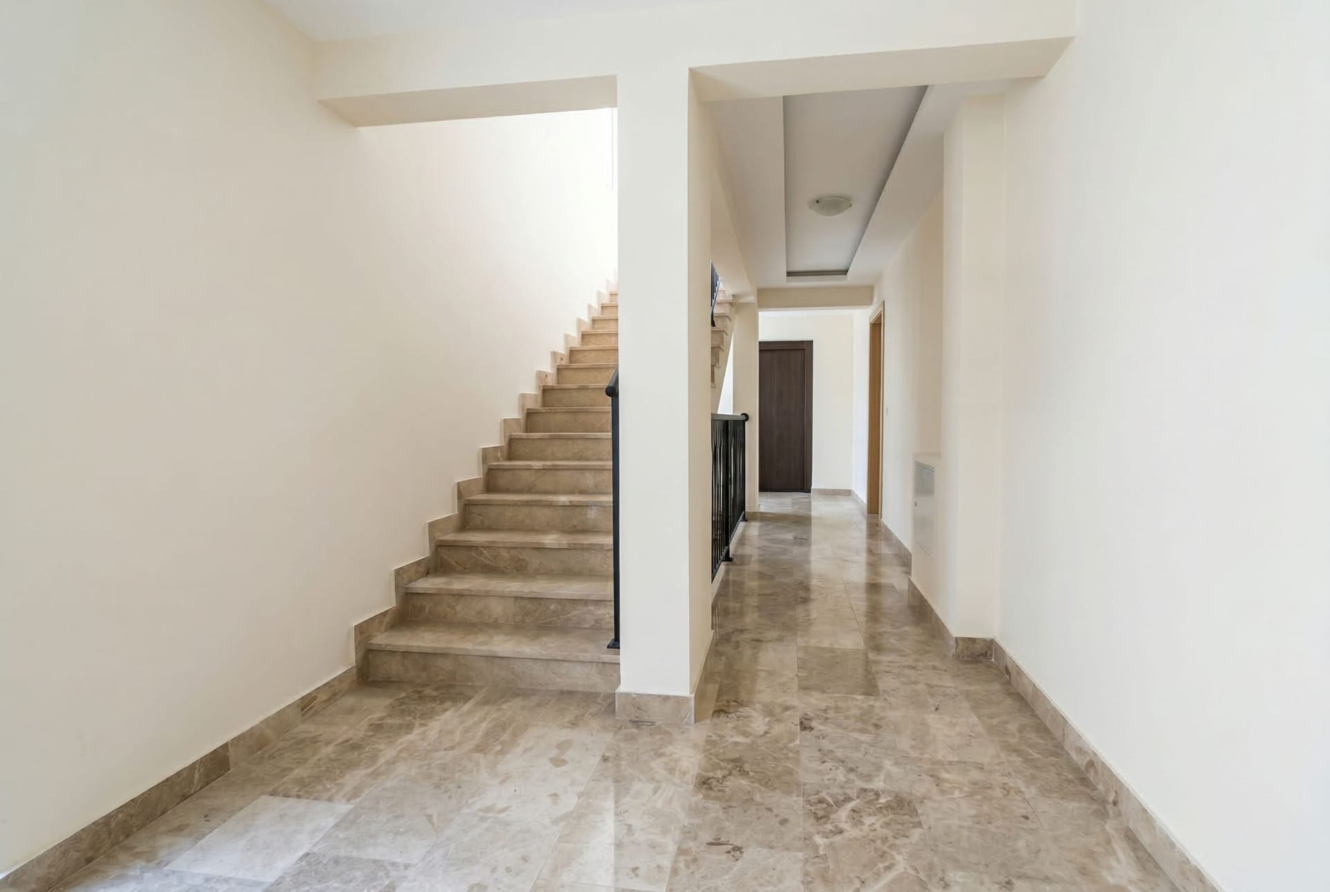 Bright hallway with marble floor and staircase in an apartment, Pržno, Montenegro. Modern interior with white walls.