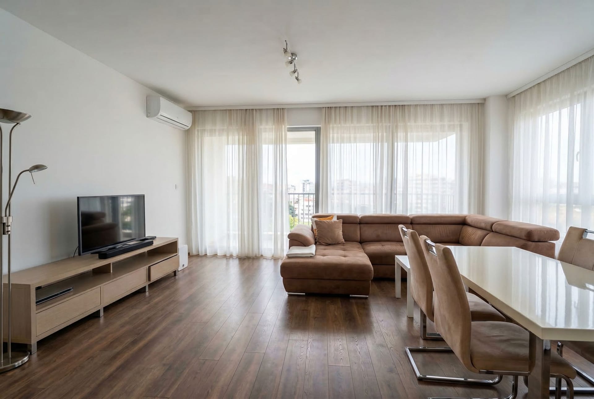 Bright living room with a brown corner sofa and dining area in an apartment, Pržno, Montenegro.