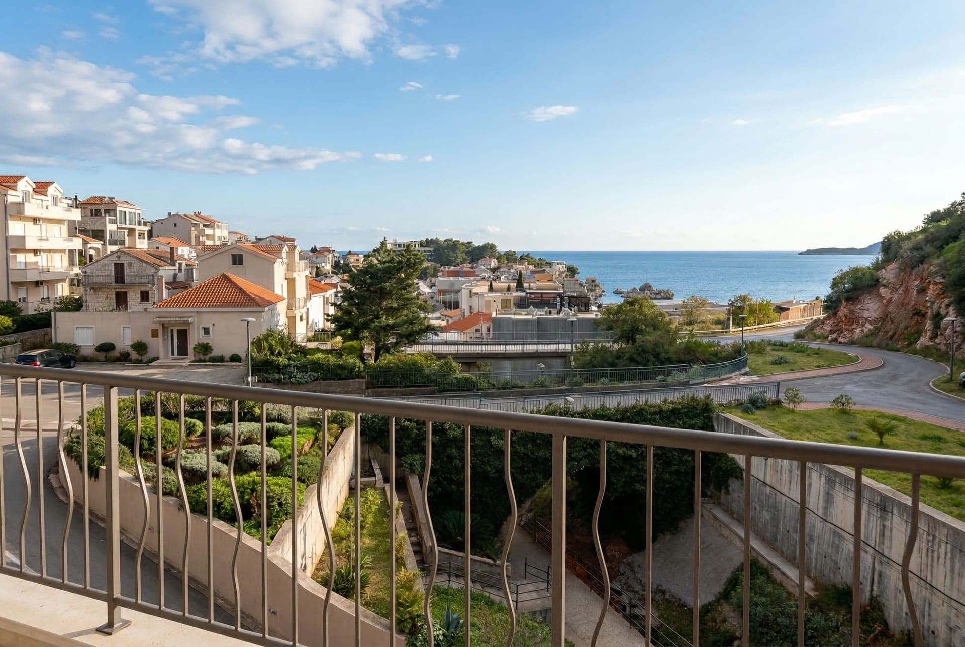 View from the apartment balcony in Pržno, Montenegro: a panorama of the sea, Mediterranean houses, and green landscape.