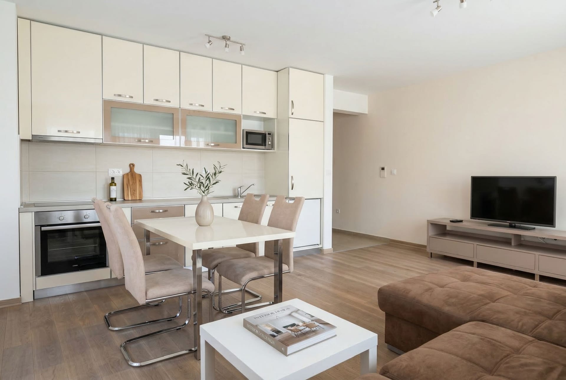 Modern kitchen-living room in an apartment in Pržno, Montenegro: light cabinetry, dining area, and a soft sofa.