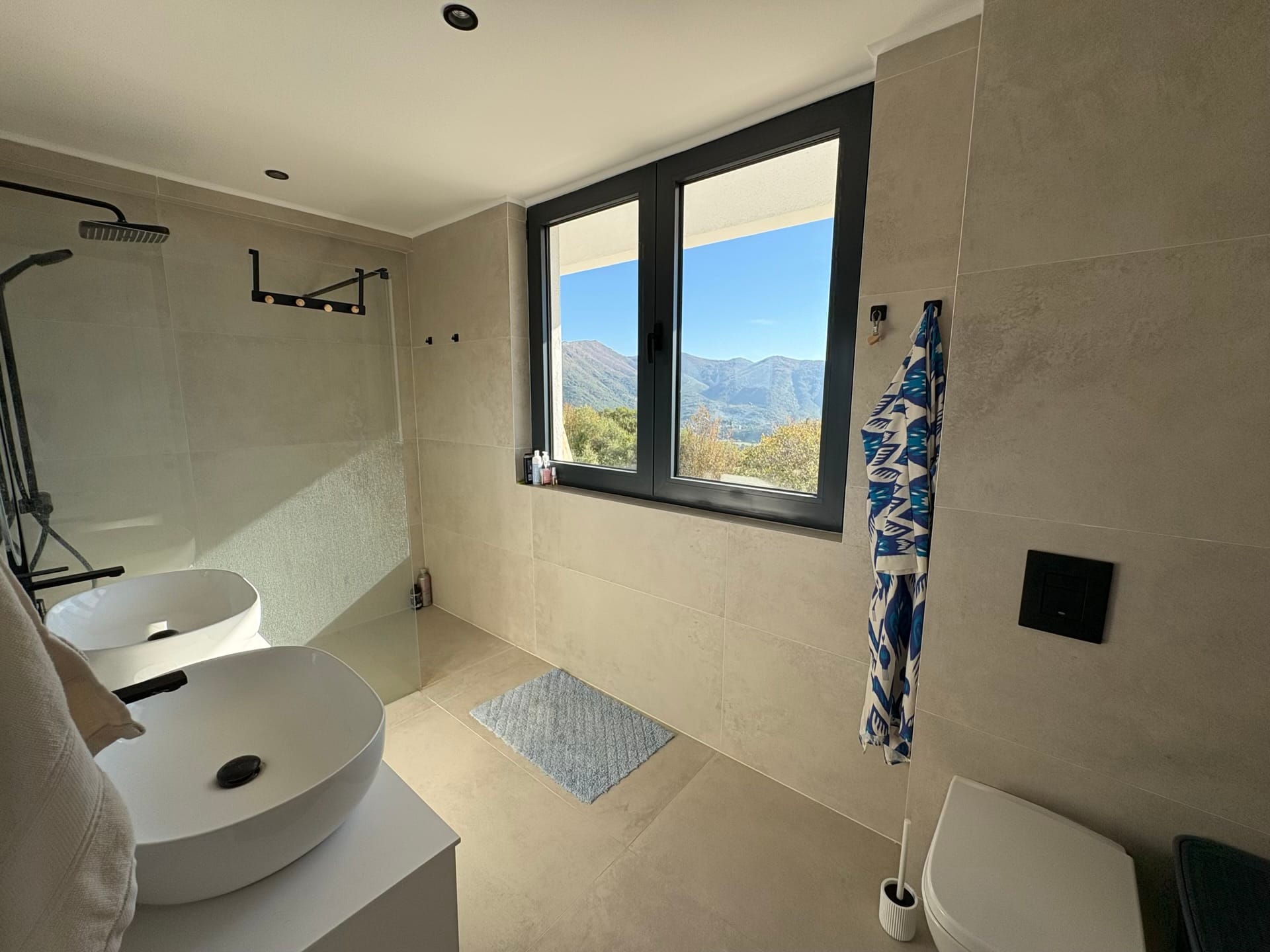 Modern bathroom with mountain views in a residential complex, Herceg Novi, Montenegro: two sinks and a shower cabin.