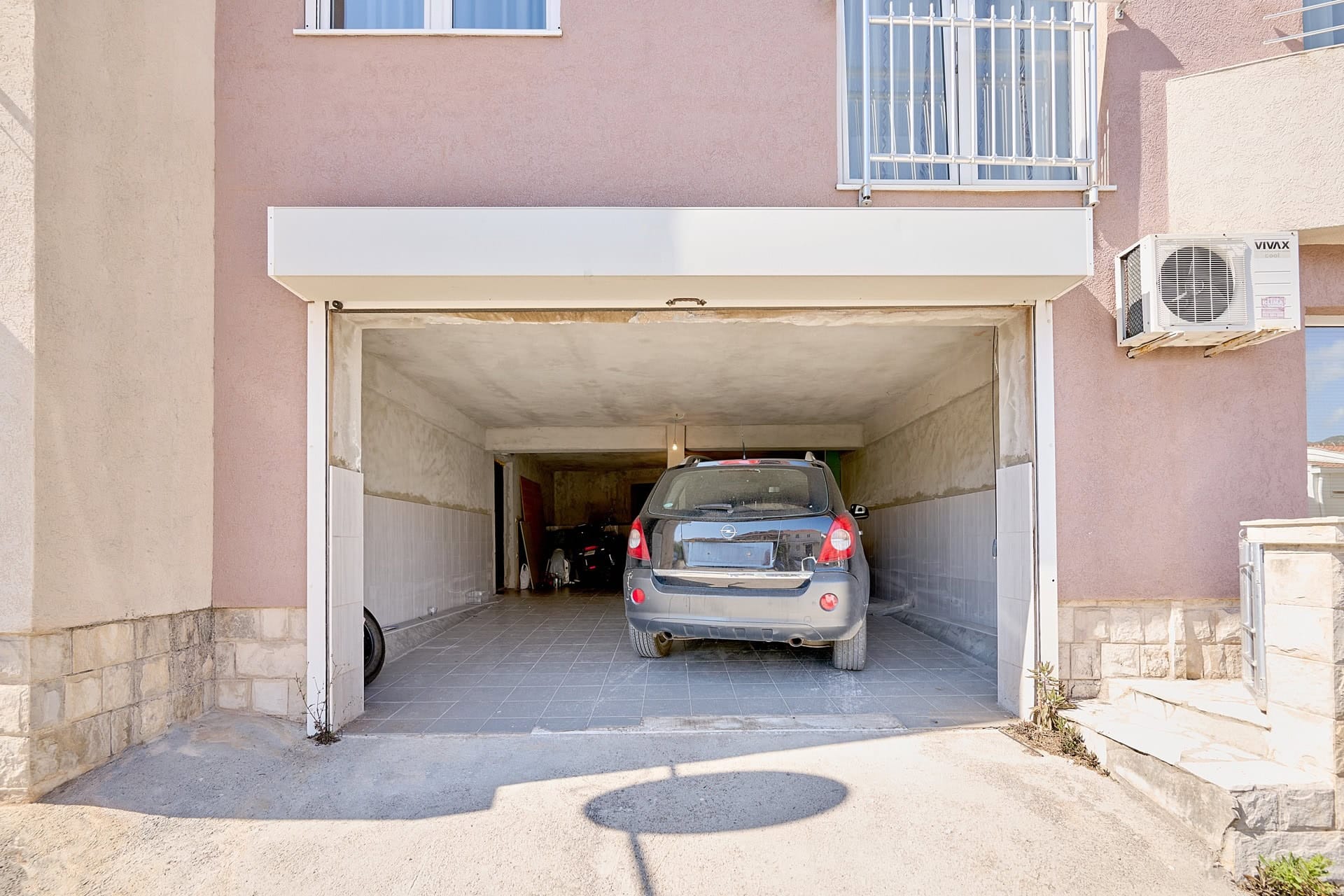 Privatna garaža sa automobilom u stambenoj zgradi u Bečićima, Crna Gora: pločice na podu, završna obrada zidova i rolo vrata.