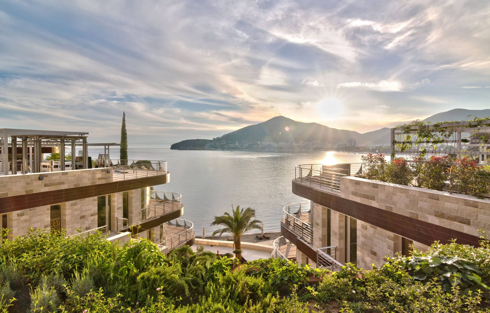 Modern villas with terraces by the sea in Budva, Montenegro: sunset, mountain, and landscaped complex grounds views.