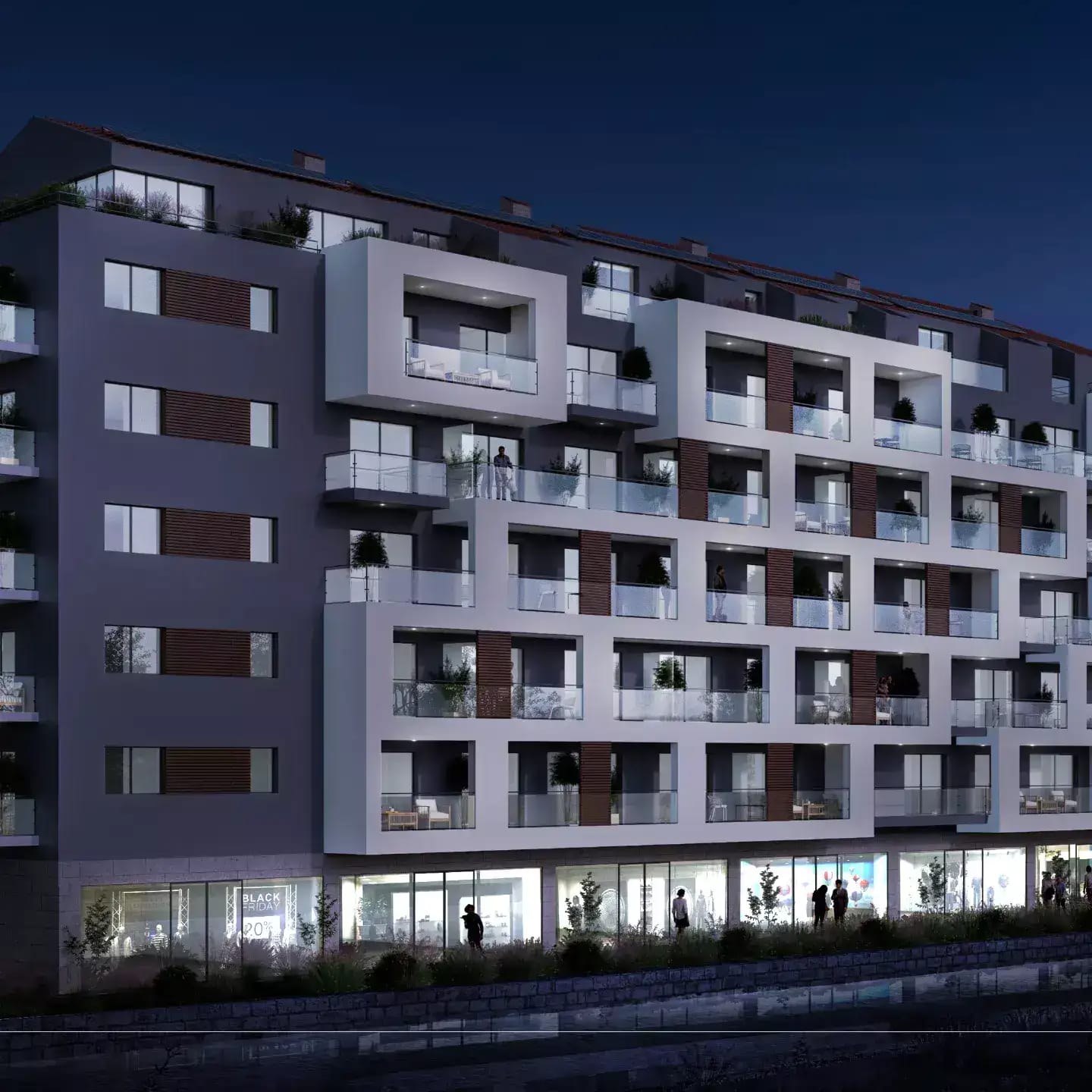 Modern residential complex with terraces and commercial spaces in Budva, Montenegro, night view of the building facade.