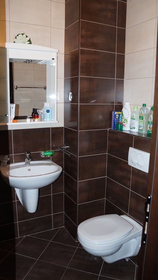 Savremeno kupatilo u stanu u Budvi, Crna Gora: viseća WC šolja, umivaonik i pločice u braon tonovima.