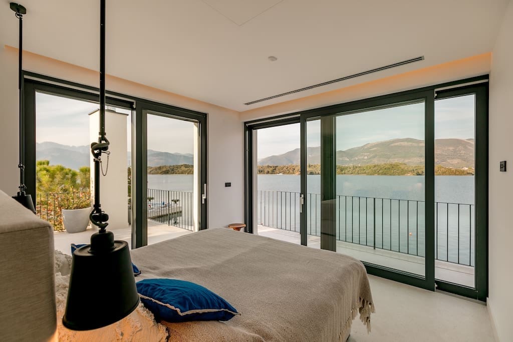 Spavaća soba u vili u Luštici, Crna Gora: panoramski prozori s pogledom na more, moderan enterijer i izlaz na terasu.