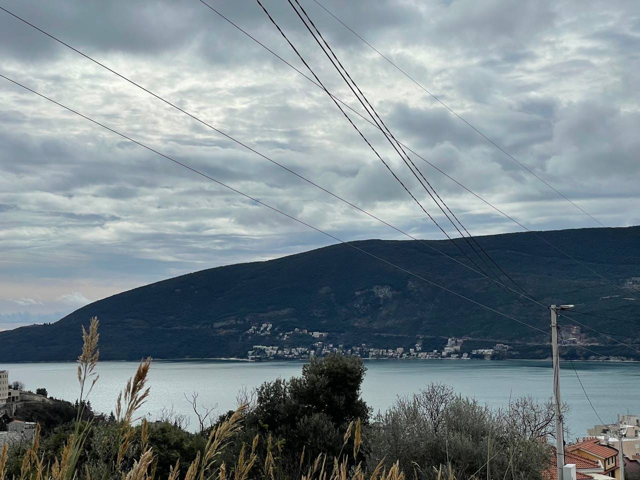 Panoramablick auf das Meer und die Berge von einem Grundstück in Herceg Novi, Montenegro, bei bewölktem Wetter.