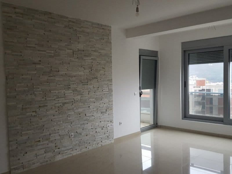 Helles Wohnzimmer in einer Wohnung in Dobrota, Montenegro: Akzentwand aus dekorativem Stein und Zugang zum Balkon.