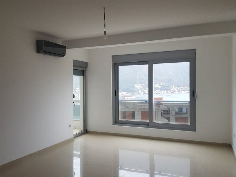 Helles Wohnzimmer in einer Wohnung in Dobrota, Montenegro: Panoramafenster mit Meerblick, Klimaanlage und Fliesenboden.